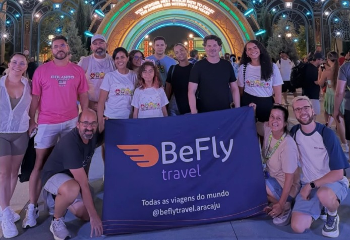 Grupo de viajantes da BeFly Travel Aracaju em Orlando, ao lado da bandeira da empresa