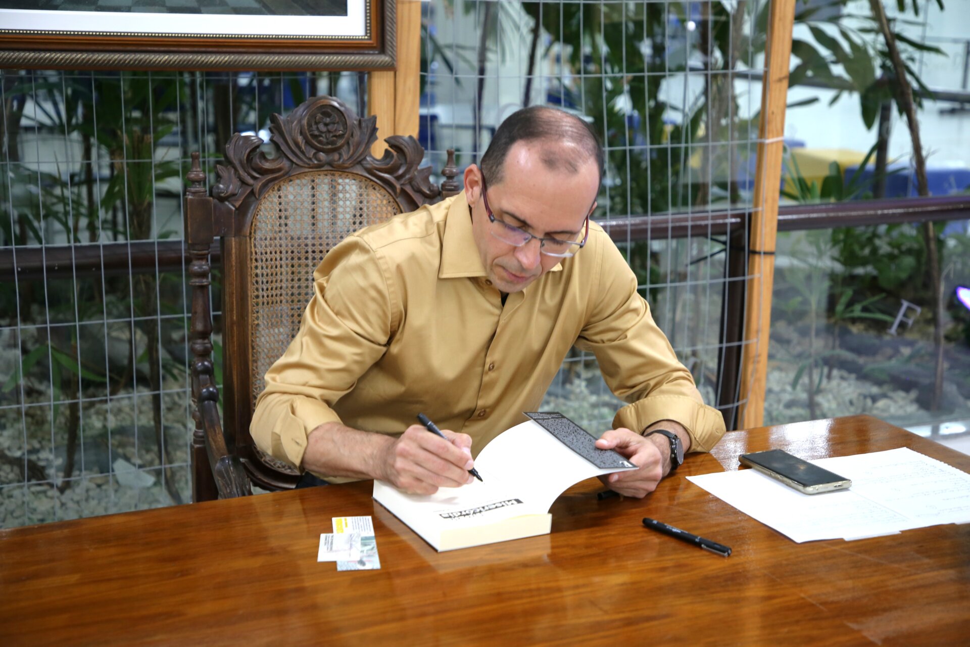 O professor Rooseman Oliveira Silva autografa exemplar do livro Tiro de Misericórdia no lançamento na Unit