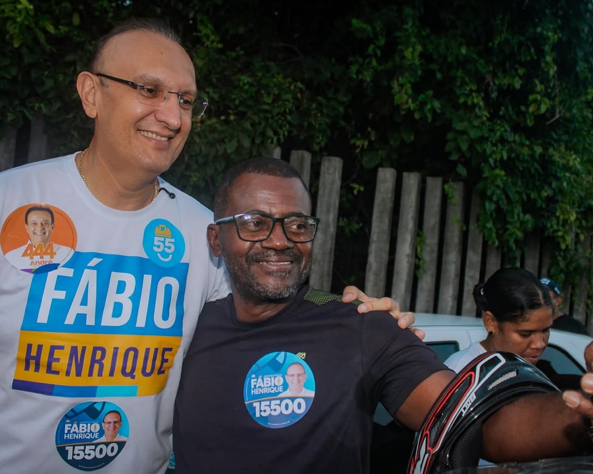 Fábio Henrique sorri ao lado de um apoiador, ambos usando camisetas de campanha com os números 15500 e 444