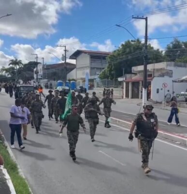 Grupo de veteranos do GVEB em trajes militares desfila por rua do bairro 18 do Forte, em Aracaju, carregando bandeira verde